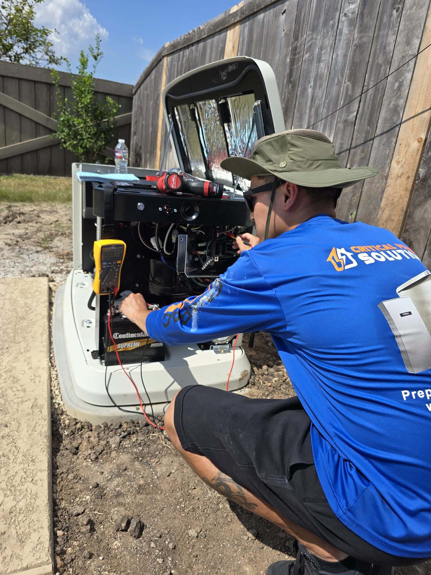 A Critical Power Solutions technician testing a standby generator's control board with a multimeter